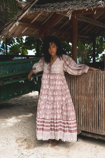 Jasmine Maxi Dress Lavender — outdoor lifestyle under thatched roof, tropical beach setting, full length showing tiered lavender maxi, hand block print cotton, artisan ethical boho maxi dress | Daughters of India